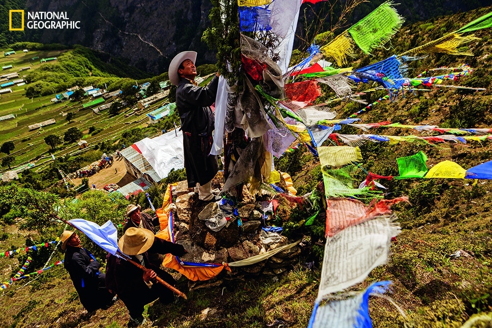 Photo by Aaron Huey/National Geographic Elders attach prayer flags outside Phortse at an altar for Khumbila, the god of the Khumbu.